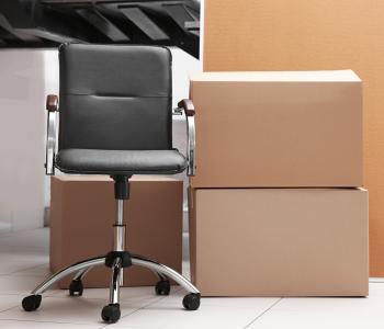 Office chair and two cardboard boxes on a tiled floor.