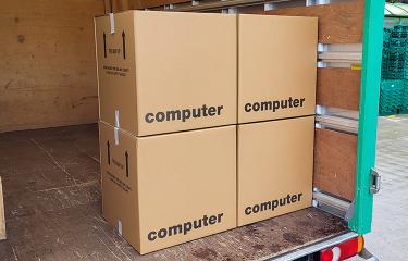 Four cardboard boxes labeled "computer" secured in a moving truck.